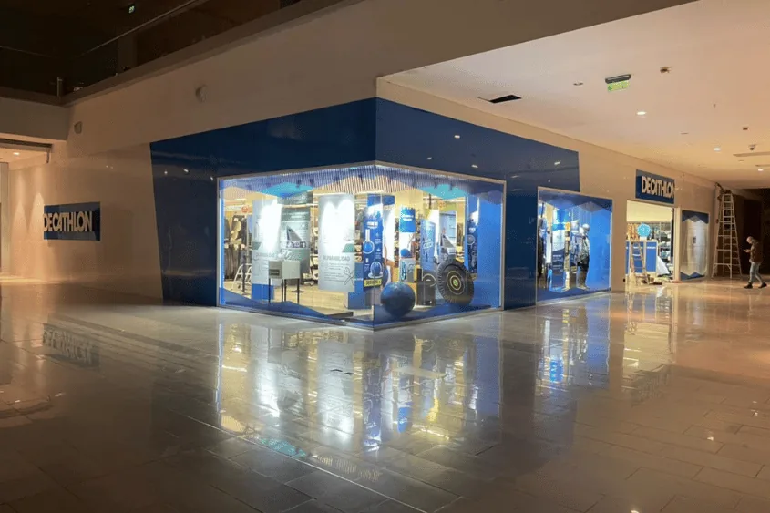 Acceso iluminado a una tienda Decathlon en un centro comercial.