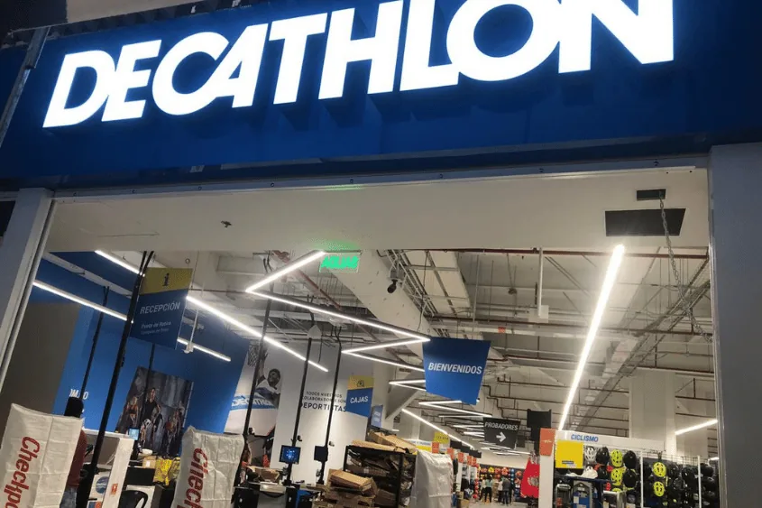 Interior de una tienda Decathlon con seu00f1alizaciu00f3n y zona de caja.