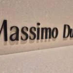 Ru00f3tulo de Massimo Dutti sobre el paramento de piedra de la fachada.