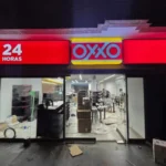 Fachada de una tienda OXXO de noche, con el interior en montaje.